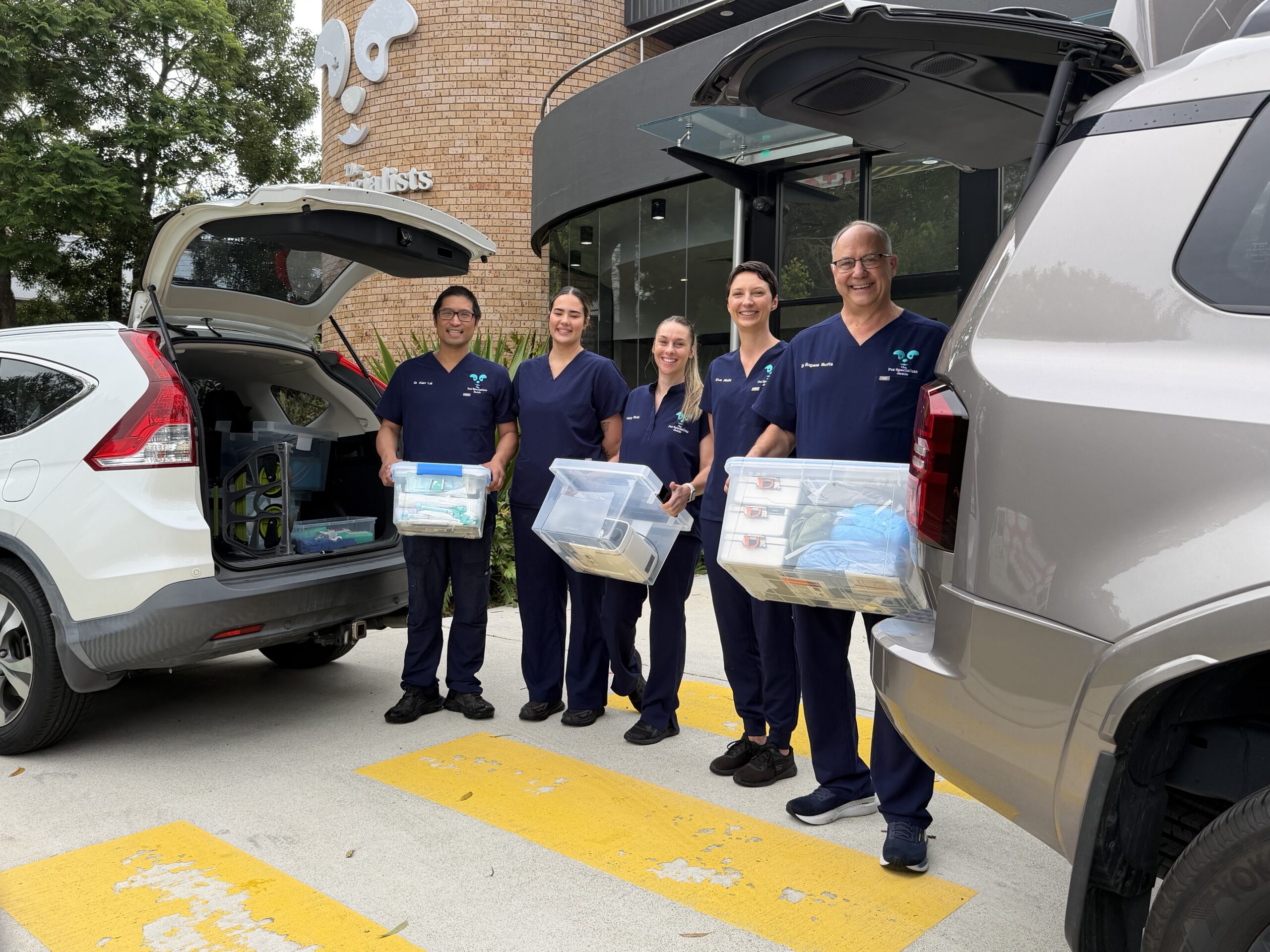 Two smiling female medical or dental professionals standing back-to-back, one in a white coat and one in green scrubs, symbolizing teamwork and expertise.